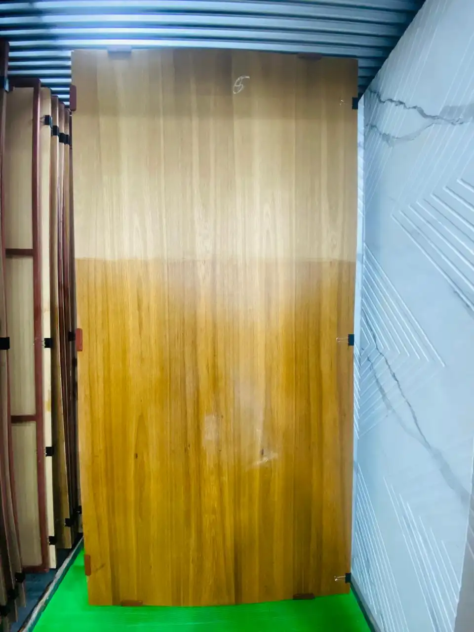 Teak-veneered door sheet in the display rack, shown half-polished