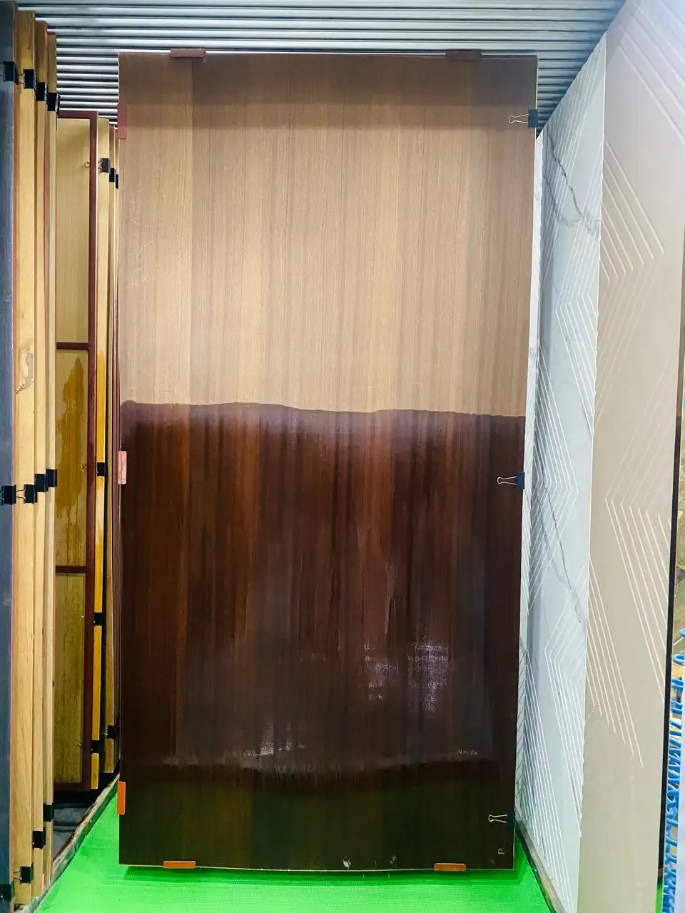 Dark walnut-finish door sheet displayed half-polished in the rack
