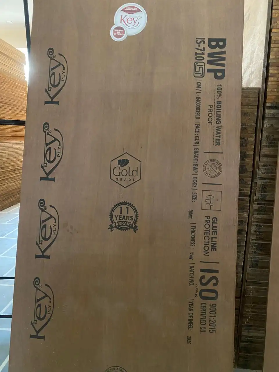 Key Ply BWP boiling-water-proof plywood sheet stamped IS-710, with plywood stacks behind