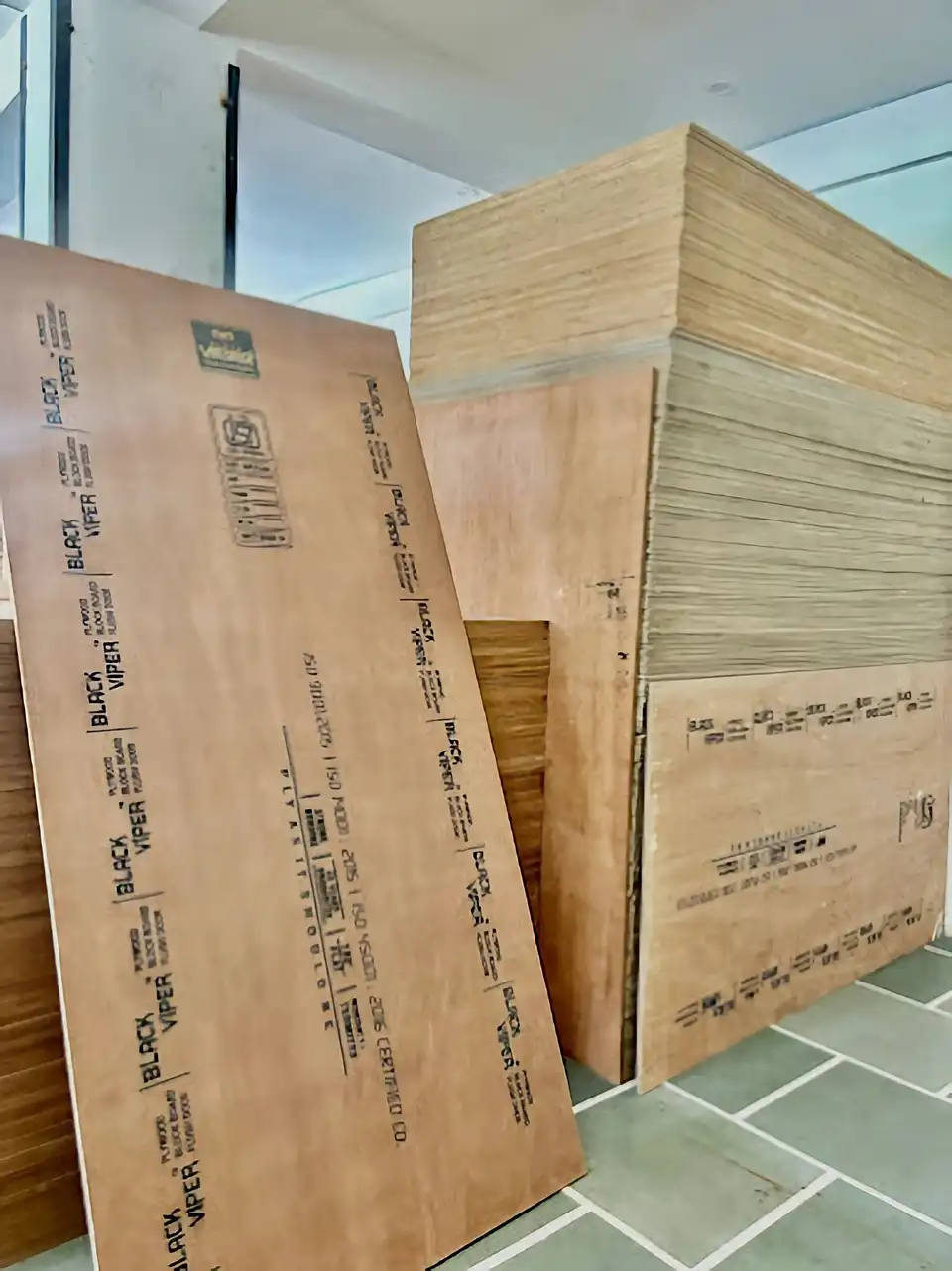 Black Viper branded plywood sheet displayed in front of a tall stack of boards