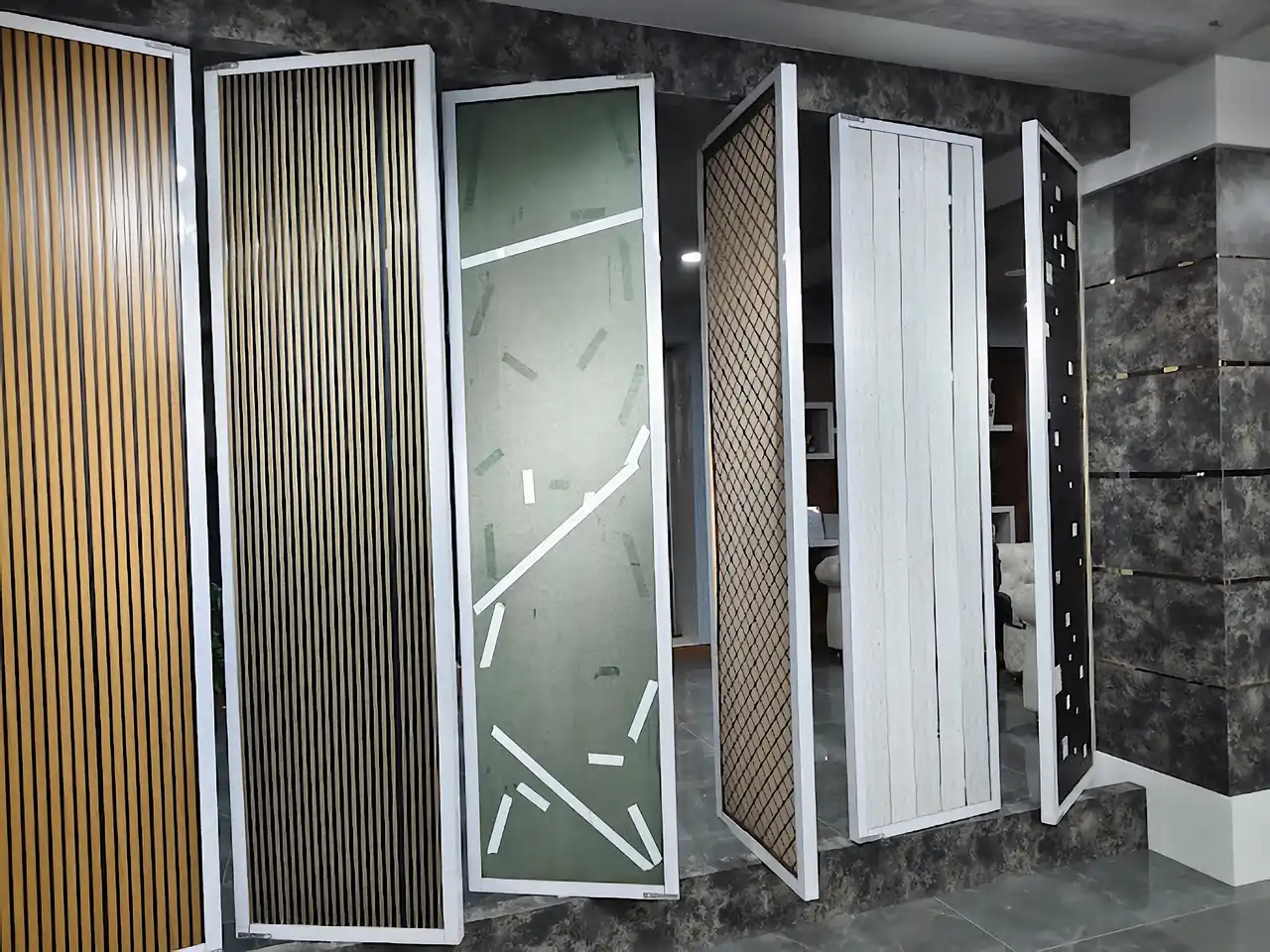 Six decorative wall panel samples displayed on a stone platform in the showroom